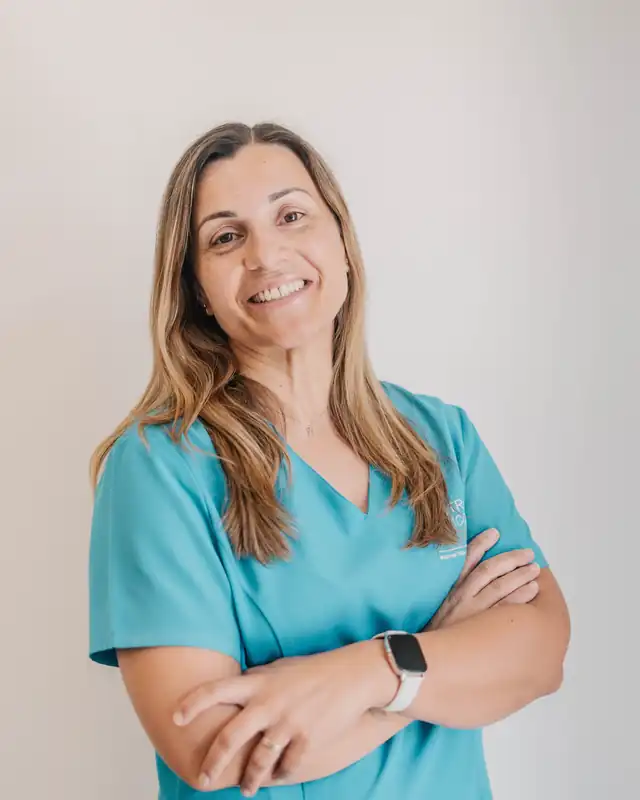 Cristina Domingos, enfermeira, de farda azul-turquesa, de braços cruzados, a sorrir.