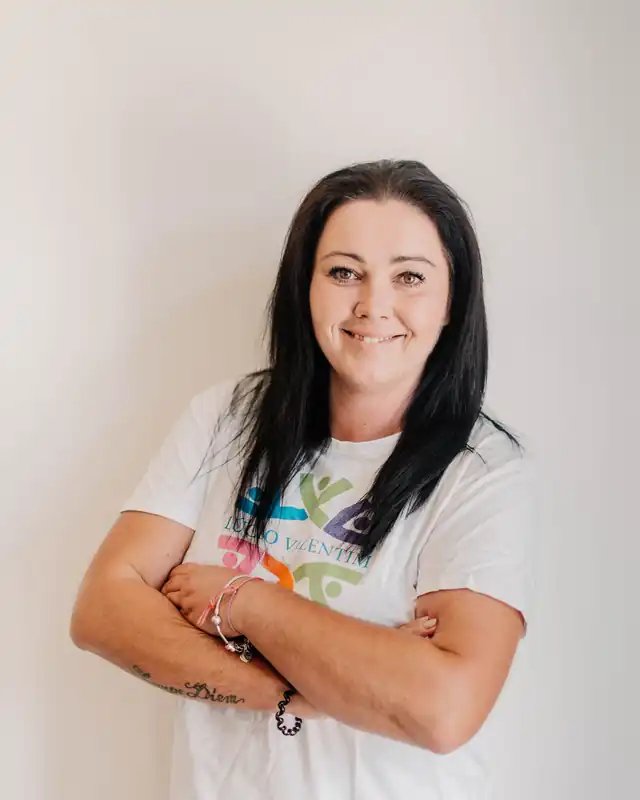Iwona, equipa técnica, com a camisola da instituição, de braços cruzados.