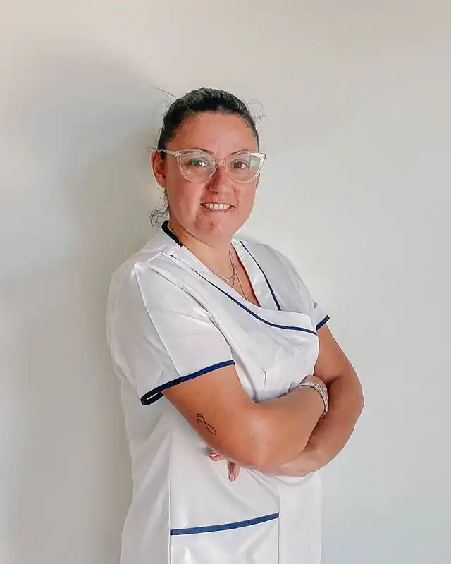 Rita Madeira, fisioterapeuta, de farda branca e óculos, de braços cruzados.