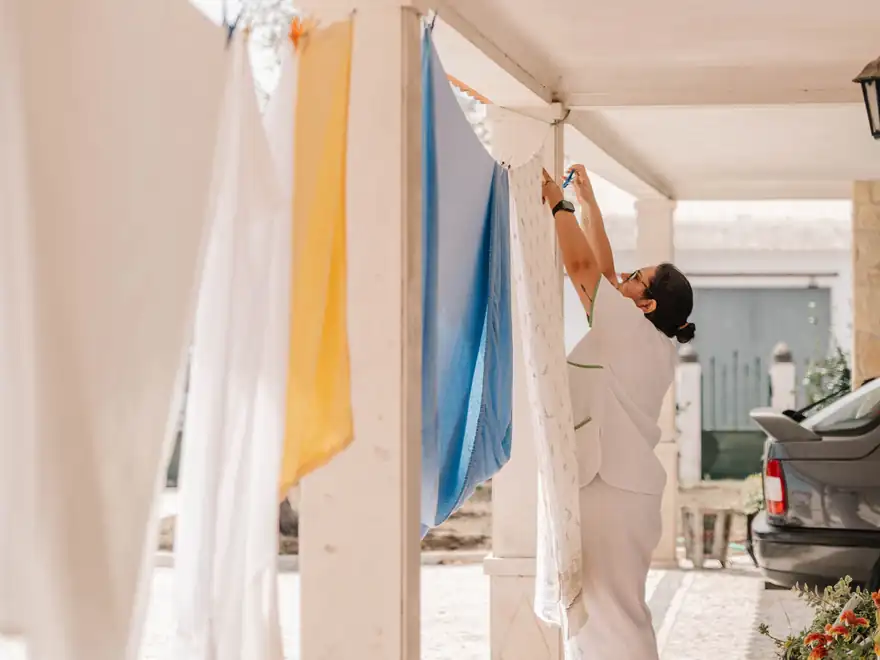 Roupa lavada a secar num alpendre, estendida por uma profissional da associação.